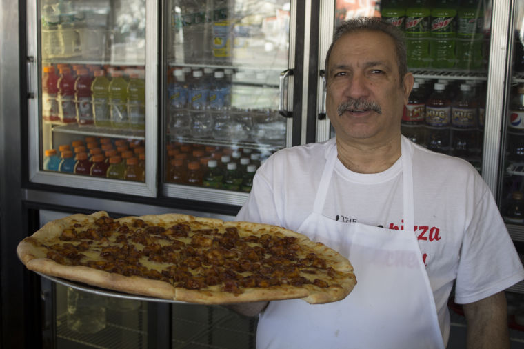 Sergio Retta, a chef at The Iron Pizza Kitchen, holds a barbecue chicken pizza.